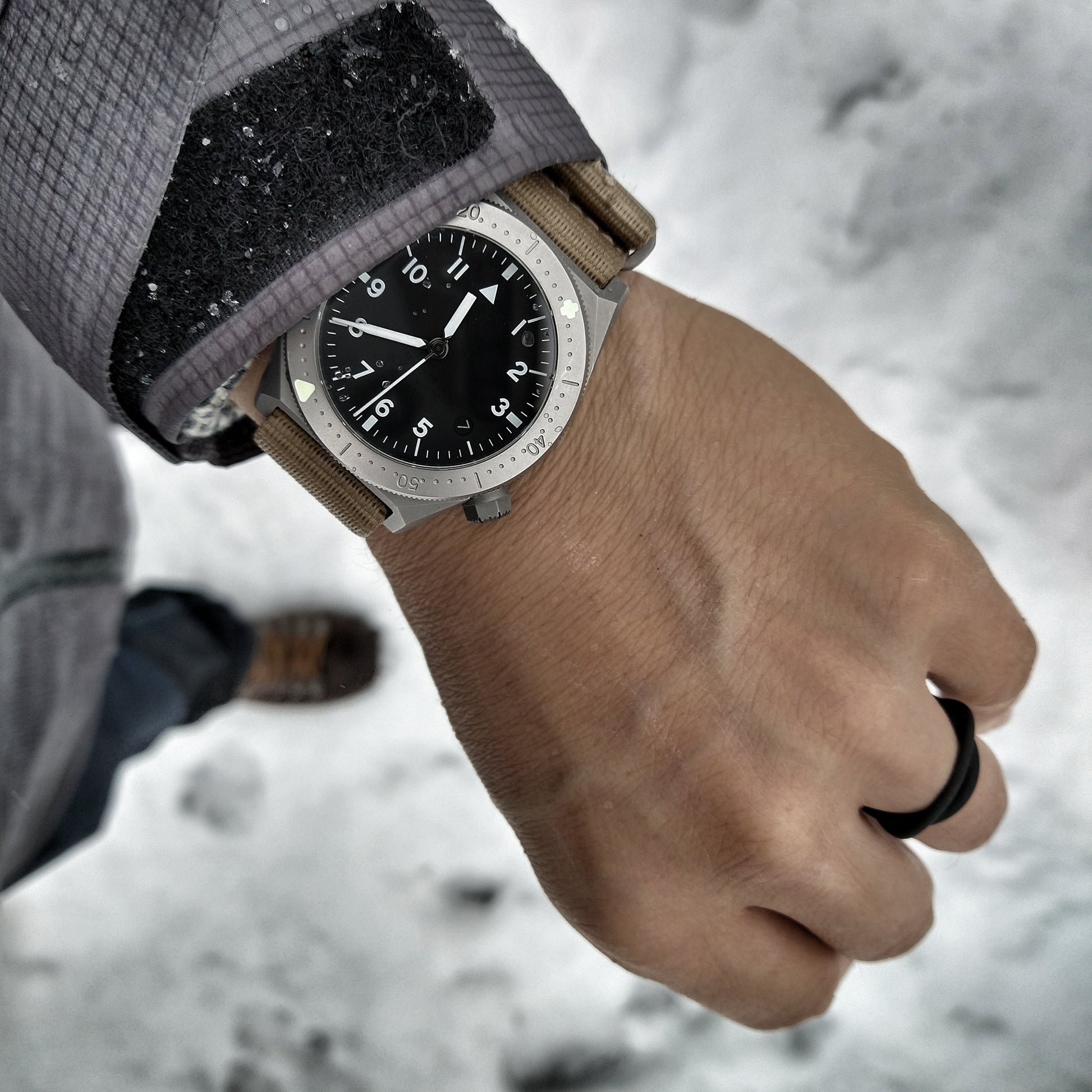 Hand wearing a watch with a blurred snowy background