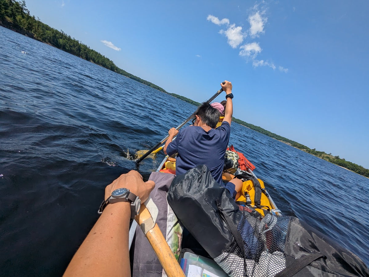 A SCOUT wearer paddling a canoe with family on a lake.